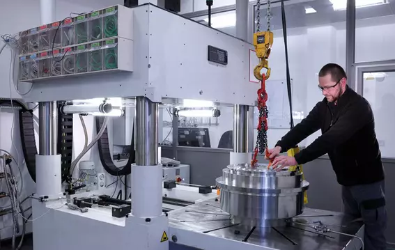 Technician assembling an industrial component on a large machine system.