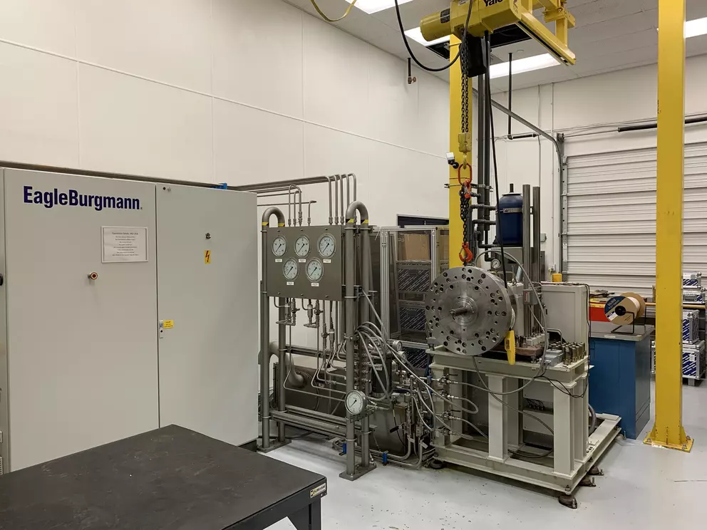 Industrieller Prüfstand von EagleBurgmann mit Hydraulikleitungen, Messinstrumenten und schwerem Prüfgehäuse in einer technischen Laborumgebung.
