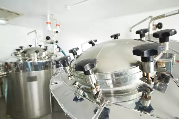 Stainless steel industrial processing vessel with sealed lid in a hygienic production environment.