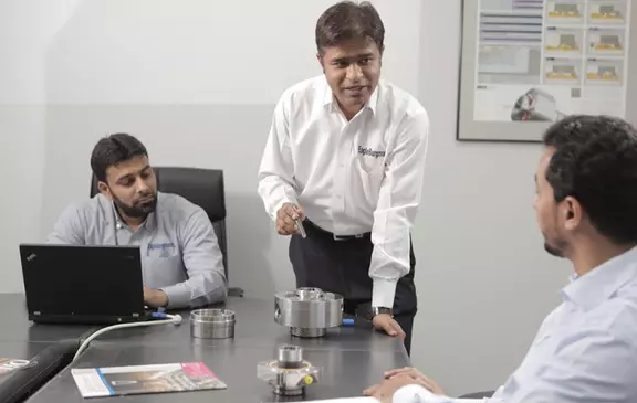EagleBurgmann professionals discuss industrial sealing components during a technical meeting in an office setting.