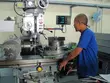 Technician operating precision machining equipment in an industrial workshop, manufacturing or finishing a mechanical seal component in a technical production environment.