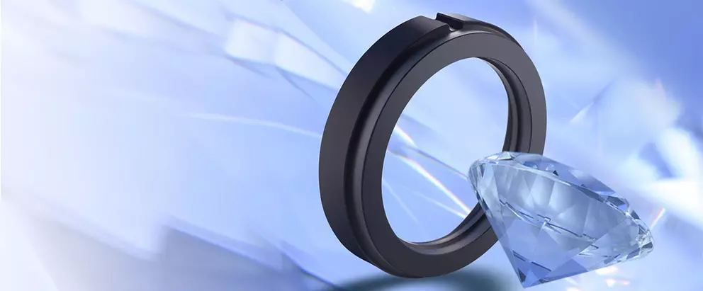 Ein schwarzer mechanischer Dichtungsring, der aufrecht neben einem großen, blauen, facettierten Diamanten auf einem hellblauen abstrakten Hintergrund mit prismenartigen Reflexionen positioniert ist.
