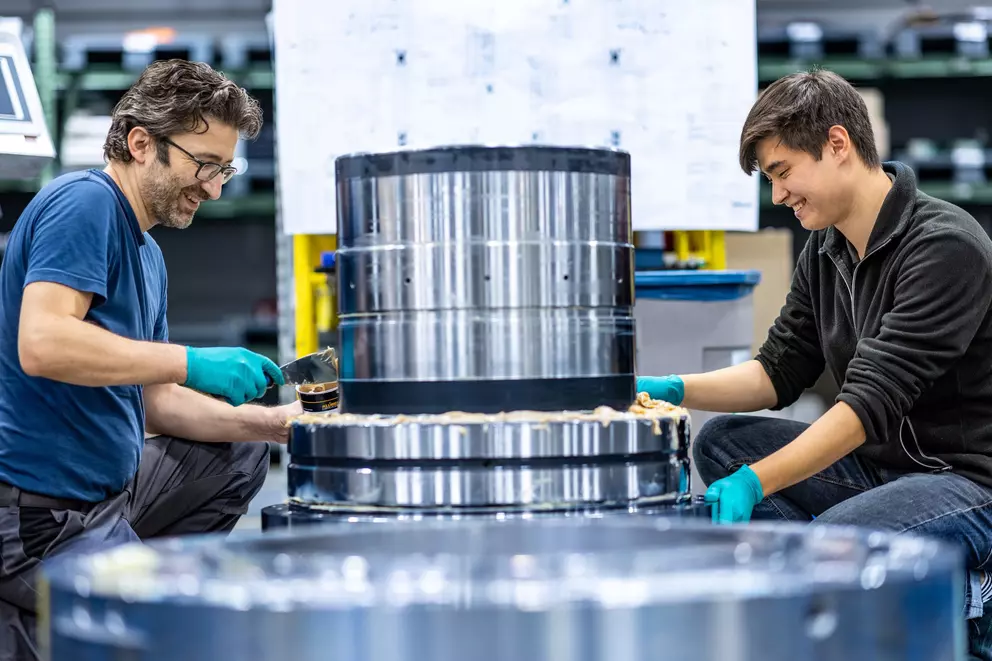 EagleBurgmann technicians assembling and applying sealant to a large industrial mechanical seal component, showcasing precision engineering, teamwork, and manufacturing expertise.
