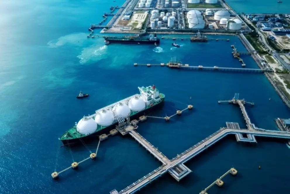 Aerial view of LNG terminal with liquefied natural gas carrier docked for loading and unloading operations at an industrial coastal facility.