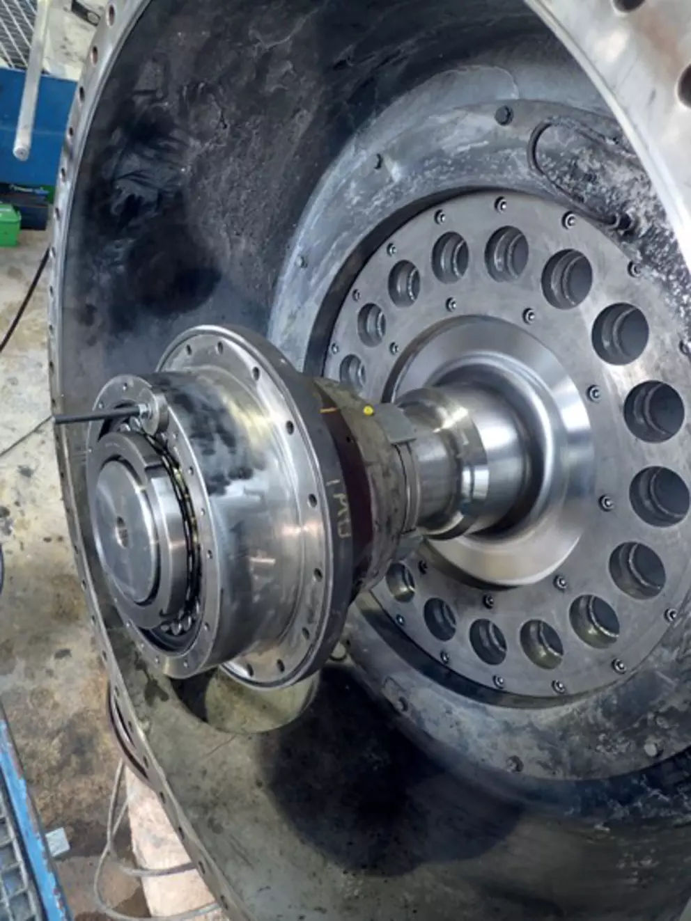 The image depicts a stainless steel piping system with a deformed white expansion joint at the connection, held in place by black straps.
