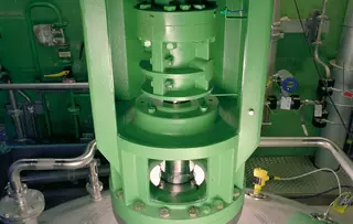 Close-up of an industrial agitator drive with shaft and connected piping.