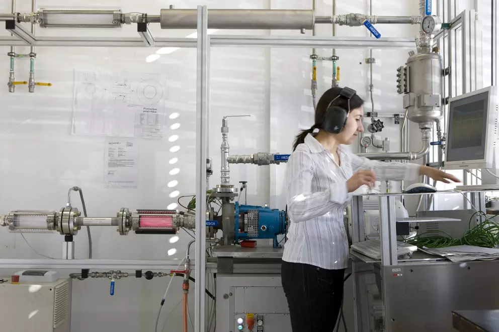Laborantin bedient industrielle Prüf- und Messtechnik zur Analyse von Strömungs- und Prozessdaten in einer modernen Forschungseinrichtung.