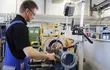 En tekniker, der betjener industrimaskiner i et EagleBurgmann-værksted, hvor han inspicerer og bearbejder en mekanisk tætningskomponent i et moderne produktionsmiljø.