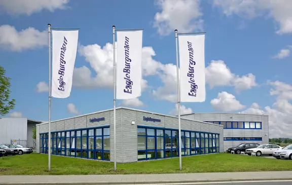 Exterior view of the EagleBurgmann Espey facility with company flags in front.