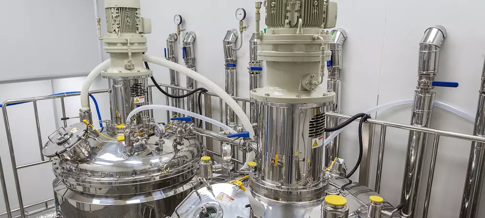 Edelstahl-Mischbehälter mit Motoren und Messgeräten in einer sauberen Industrieanlage.