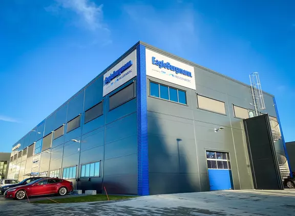 Modern EagleBurgmann office and industrial building with company signage under a bright blue sky.