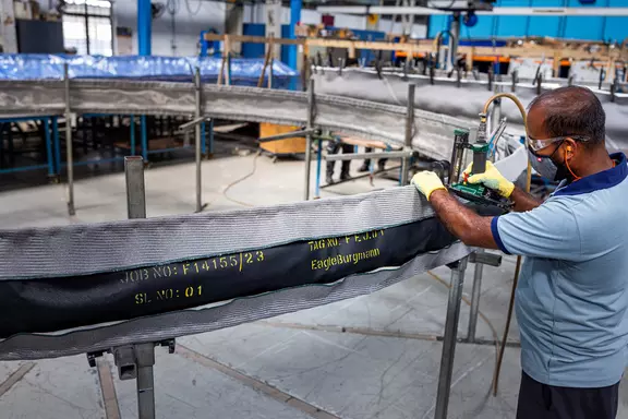 Factory worker inspecting and assembling a large fabric expansion joint for industrial ducting and high-temperature sealing applications.