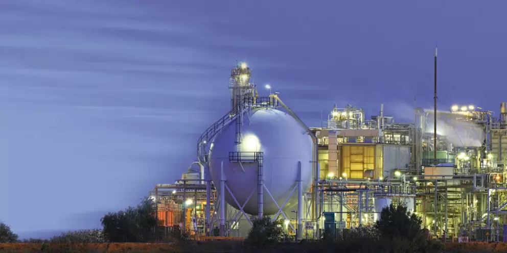 Große Industrieanlage mit Lagertank und beleuchteten Produktionseinheiten bei Nacht, ideal für Inhalte aus der Energie-, Gas- oder petrochemischen Industrie.