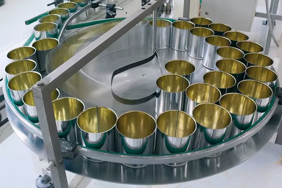 Stainless steel food processing line with circular conveyor and metal containers, representing hygienic production applications in the food industry.