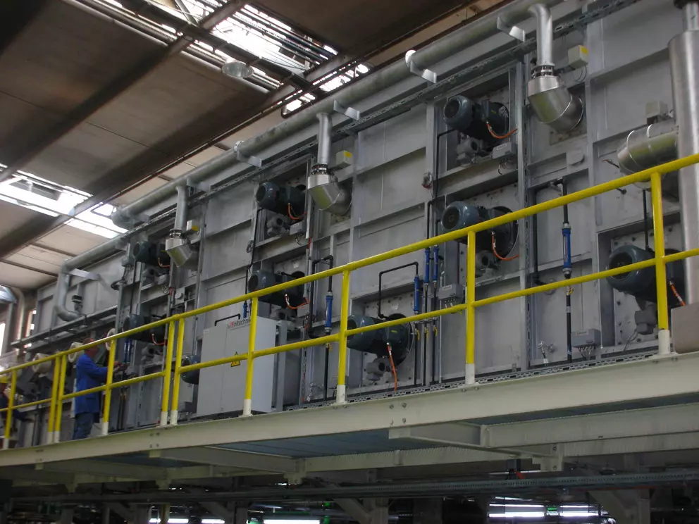 Industrial processing system with piping, motors, and service platform in a manufacturing facility.
