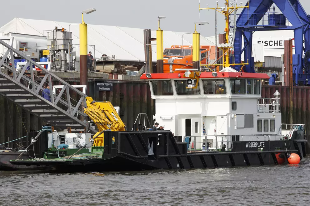 Industrielles Serviceschiff an einer Hafenanlage angedockt.