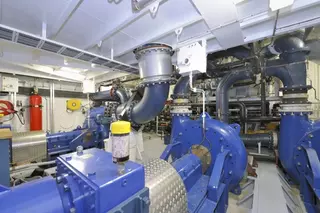 Engine room of a dredging vessel with pumps, piping, and drive technology.
