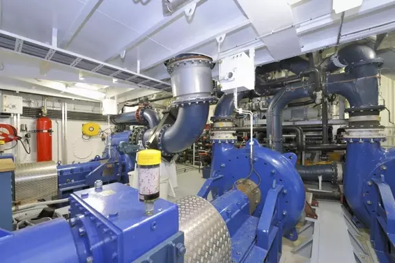 Engine room of a dredging vessel with pumps, piping, and drive technology.