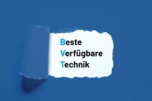 Aufgerissenes Papier, das den Text „Beste Verfügbare Technik (BVT)“ auf blauem Hintergrund freilegt.