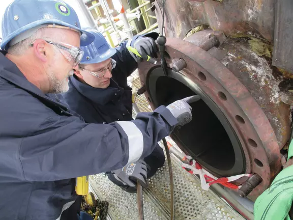 Engineers wearing safety helmets inspecting large industrial equipment and mechanical seals during maintenance work.