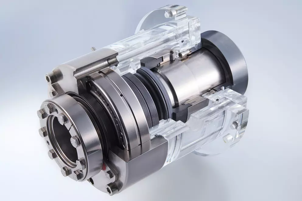 Cross-section of a complex mechanical seal, showing metallic components, rubber seals, and the surrounding transparent (acrylic/plastic) housing for demonstration purposes.