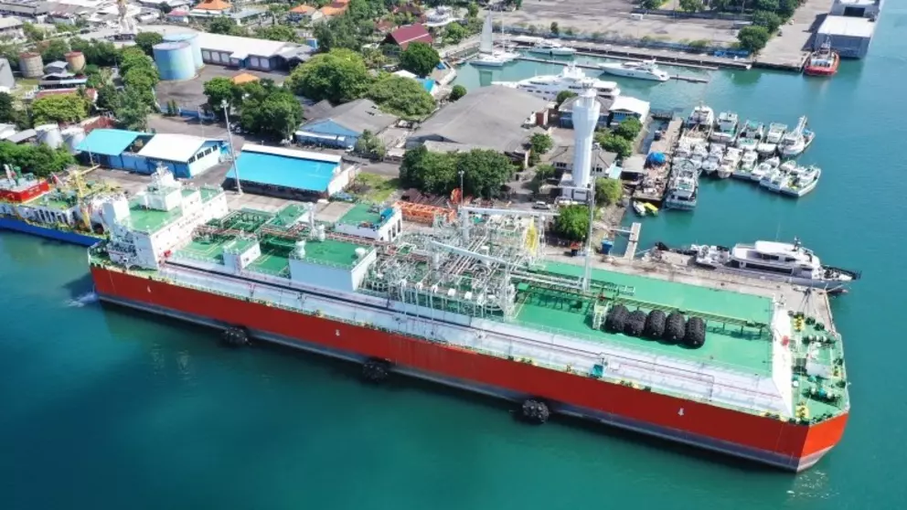 Aerial view of an LNG floating storage and regasification unit (FSRU) docked at a terminal near the coast.