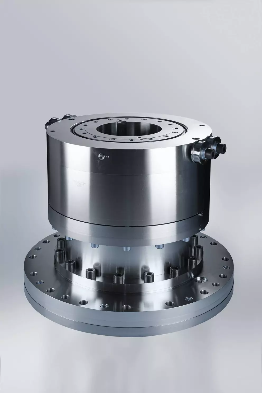 Close-up of a precision-machined, shiny metallic industrial component, likely a rotary joint or gear unit, against a plain background.