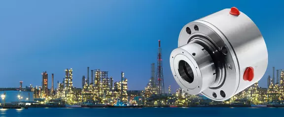 Industrial mechanical seal for refinery and petrochemical applications, shown against an illuminated plant skyline for reliable sealing in demanding process environments.
