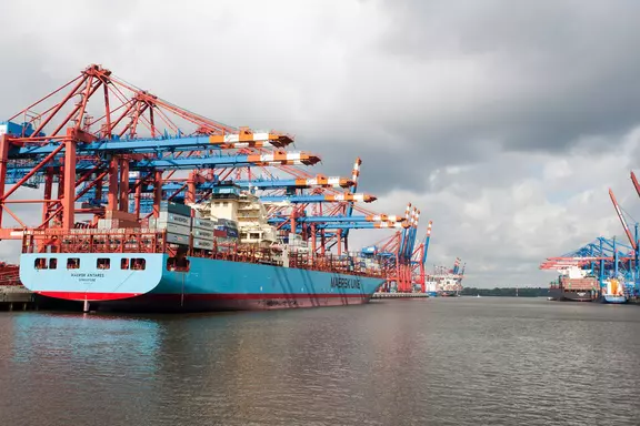 Container ship in port with gantry cranes and modern logistics infrastructure.