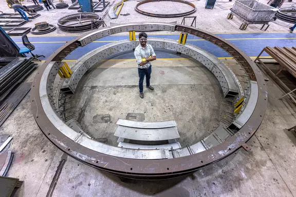 Engineer standing inside a large circular industrial expansion joint frame in a manufacturing facility for heavy-duty ducting and plant applications.