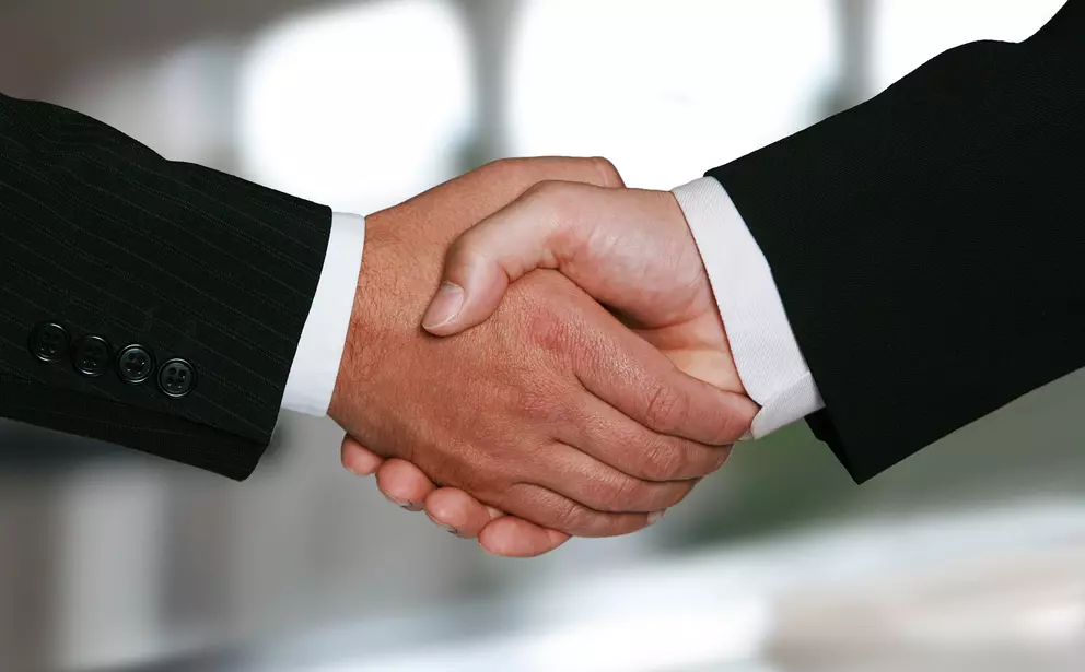 Business handshake between two people in suits.