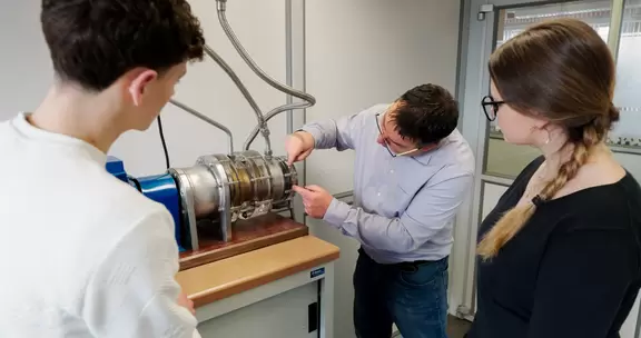 Engineers assembling and inspecting a blue industrial pump during a technical training session.