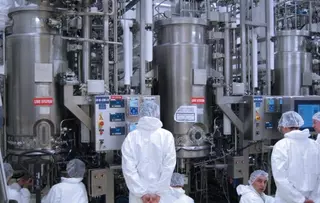 Industrial plant with process vessels and staff in protective clothing.