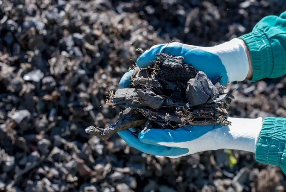 Hands holding shredded plastic waste material for recycling.