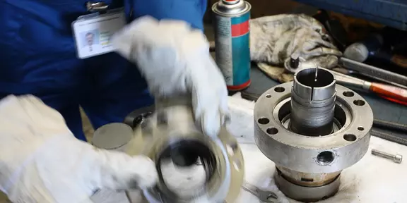 Technician wearing protective gloves inspecting or assembling mechanical seal components on a workbench, with tools and maintenance materials placed nearby.