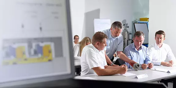 Ingenieure und Fachkräfte arbeiten gemeinsam an technischen Lösungen, Prozessoptimierung und Wissenstransfer im Rahmen eines industriellen Schulungs- und Entwicklungsprogramms.