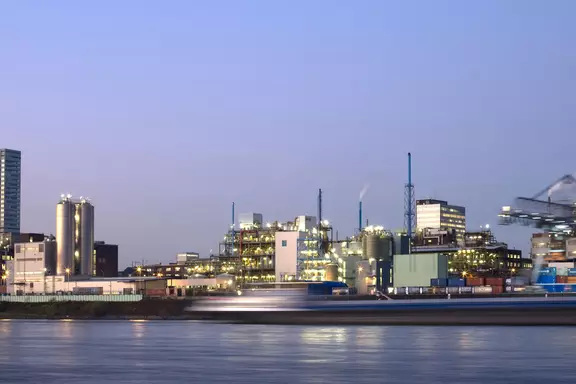 Pharmaceutical production facility by the waterfront at dusk, representing industrial applications in the pharmaceutical and life sciences industry.