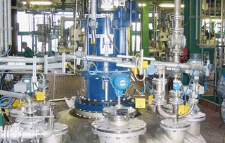Industrial plant with piping, valves, and central agitator drive.
