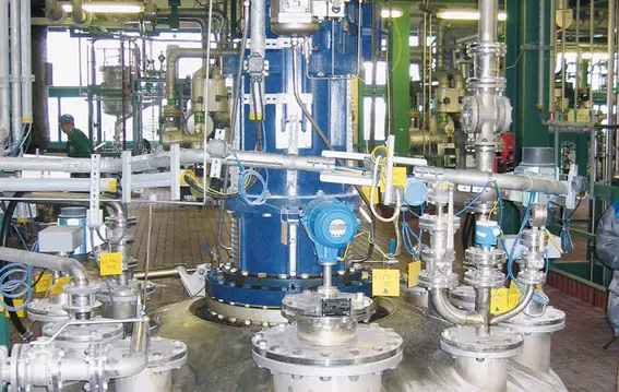 Industrial plant with piping, valves, and central agitator drive.