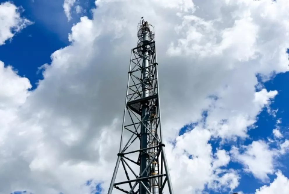 Industrial refinery or processing tower against a cloudy blue sky.
