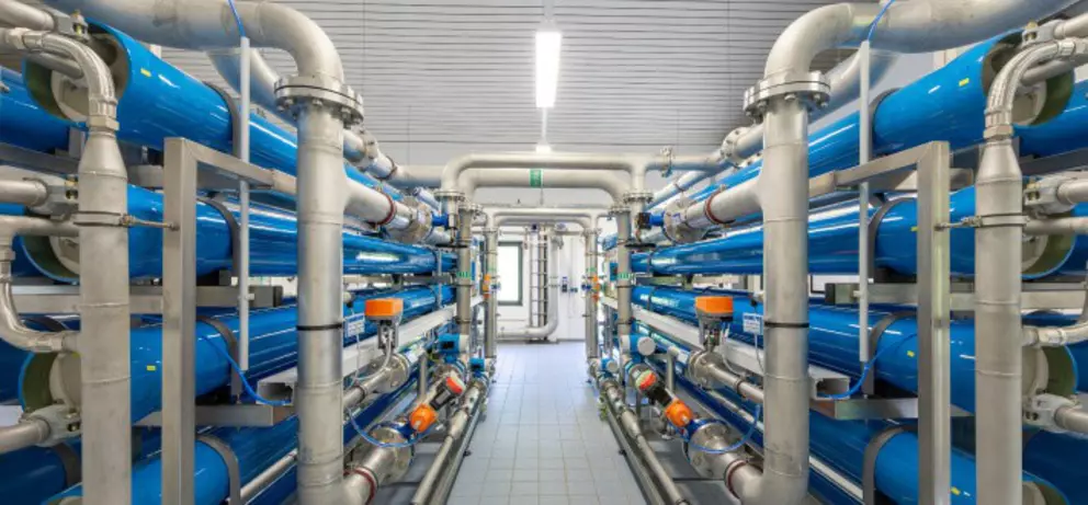 Industrial reverse osmosis water treatment system with blue filtration pipes and stainless-steel connections.