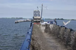 Hopper dredger handling and loading sediment on the water.