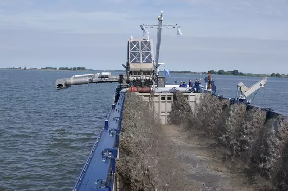 Hopper dredger handling and loading sediment on the water.