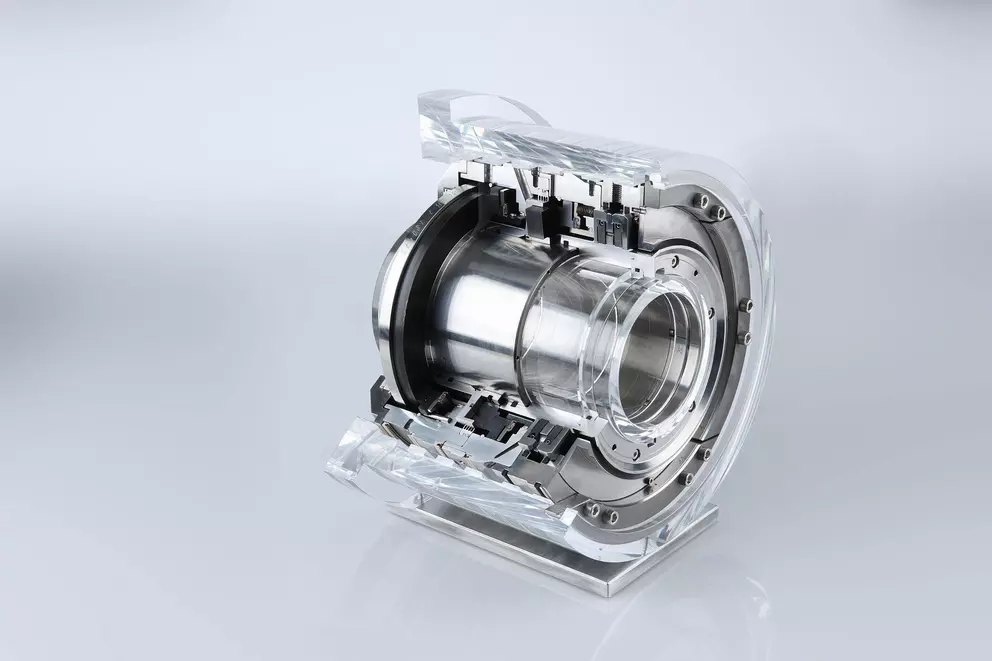 A clear acrylic cutaway model of an industrial mechanical seal or coupling, exposing the internal metallic components and complex geometry, displayed on a light gray surface.
