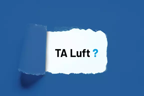 Aufgerissenes Papier, das den Text „TA Luft?“ auf blauem Hintergrund freilegt.