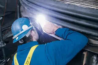Technician inspecting and welding an Inconel 625 clamshell expansion joint on an offshore turbine in the North Sea, designed to encase and protect a damaged DN 2000 bellows under high-temperature conditions.