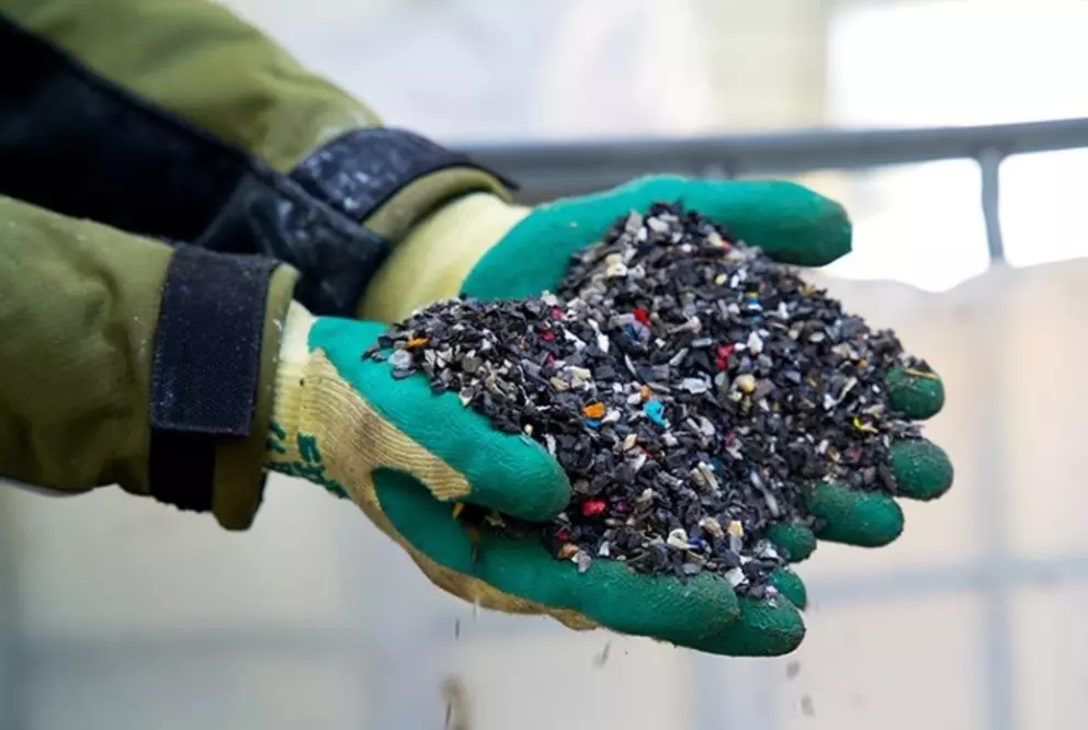 Hands holding recycled plastic granules for reuse in manufacturing.