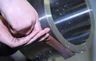 Mitarbeiter poliert ein Metallbauteil einer Gleitringdichtung – veranschaulicht die Sicherheitsinitiative von EagleBurgmann Deutschland, die durch Automatisierung manuelles Polieren und Arbeitsunfälle deutlich reduziert hat.