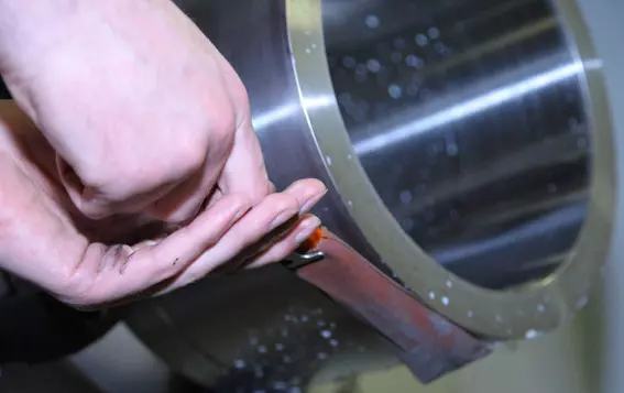 Mitarbeiter poliert ein Metallbauteil einer Gleitringdichtung – veranschaulicht die Sicherheitsinitiative von EagleBurgmann Deutschland, die durch Automatisierung manuelles Polieren und Arbeitsunfälle deutlich reduziert hat.