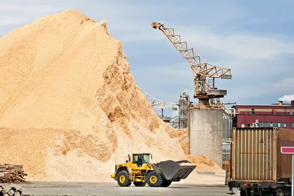 Biomass power plant with wood chips storage and heavy equipment, showcasing renewable energy production from sustainable raw materials.